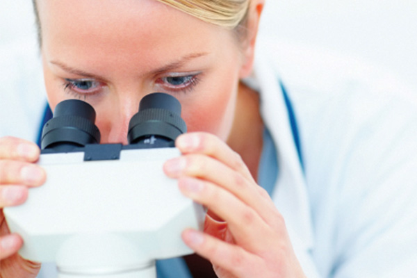 Woman looking through eyepieces of binocular microscope