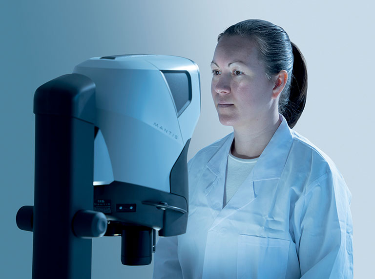Donna che guarda attraverso il microscopio stereo ergonomico Mantis